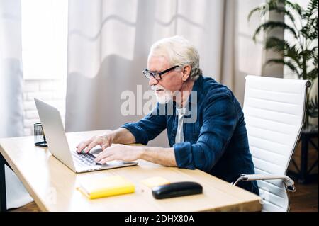 Older man is using laptop for working indoor Stock Photo