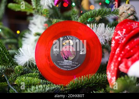 Viersen, Germany - December 9. 2020: Close up of red vintage vinyl record single with famous Elvis Presley christmas song in decorated fir tree Stock Photo