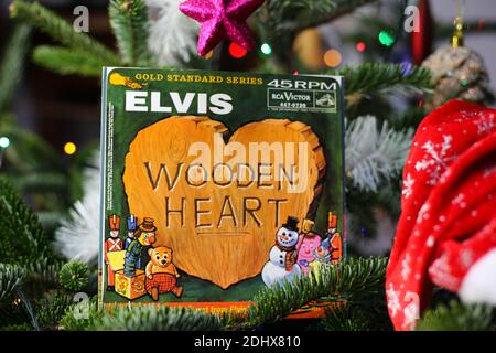 Viersen, Germany - December 9. 2020: Close up of vintage vinyl record cover single with famous Elvis Presley christmas song in decorated fir tree Stock Photo