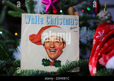 Viersen, Germany - December 9. 2020: Close up of vintage vinyl record cover single with famous Bing Crosby white christmas song in decorated fir tree Stock Photo