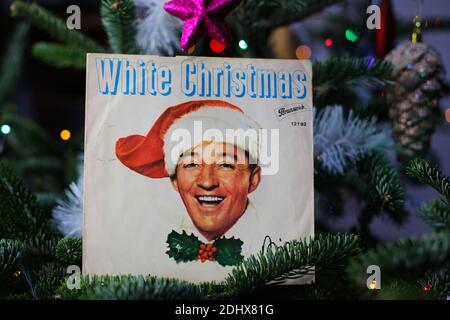 Viersen, Germany - December 9. 2020: Close up of vintage vinyl record cover single with famous Bing Crosby white christmas song in decorated fir tree Stock Photo