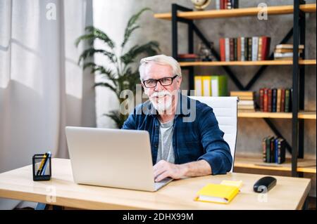 Older man is using laptop for working indoor Stock Photo