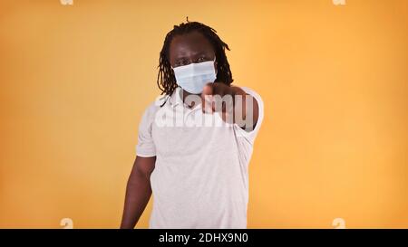 African american black man with medical mask over his face pointing finger towards camera. High quality photo Stock Photo