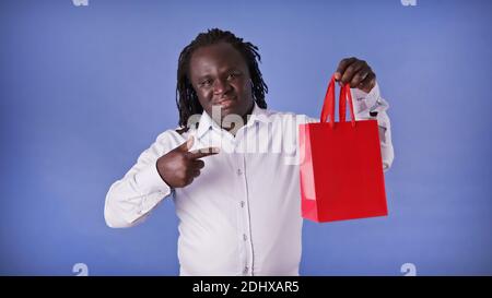Young african american black man pointing finger on the red shopping bag. Presentig the gift. High quality photo Stock Photo