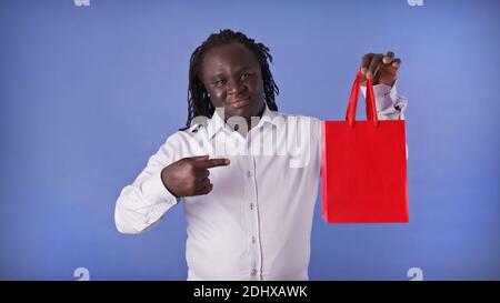 Young african american black man pointing finger on the red shopping bag. Presentig the gift. High quality photo Stock Photo