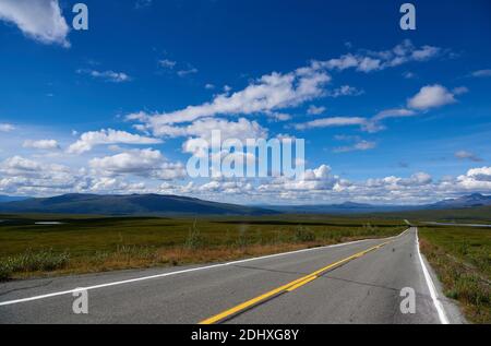 Colorful view along the paved Denali Highway into the green, treeless landscape with deep blue skies and a few, scattered clouds. Stock Photo