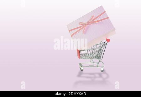 Gift boxes on 4 wheel trolley shopping cart at the pink background Stock Photo