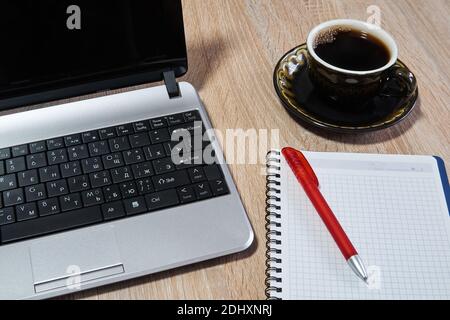 laptop, paper notebook with pen and coffee cup on the table close up Stock Photo