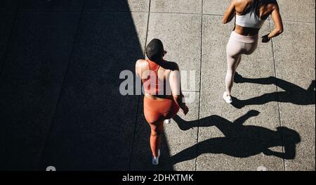 Top view of a two women in running attire jogging together. Female  friends working out together in morning. Stock Photo
