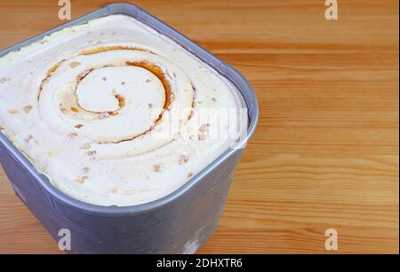 Tub of Delicious Salted Caramel Macadamia Nut Ice Cream Isolated on Wooden Table Stock Photo