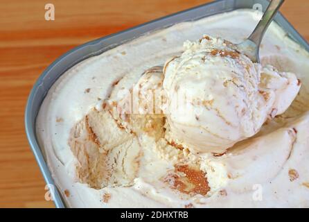 Closeup of a Spoon Scooping Delectable Caramel Macadamia Nut Ice Cream in the tub Stock Photo