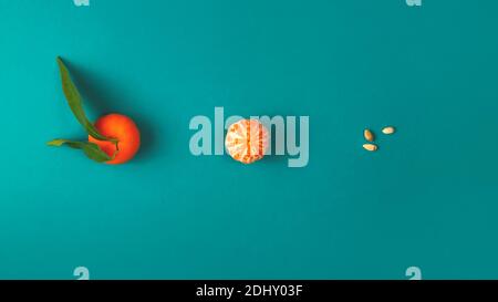 Whole tangerine, peeled and seeds on a turquoise background Stock Photo