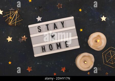 Stay Home written on lightbox among Christmas decorations Stock Photo