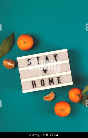 Stay Home written on lightbox among tangerines Stock Photo
