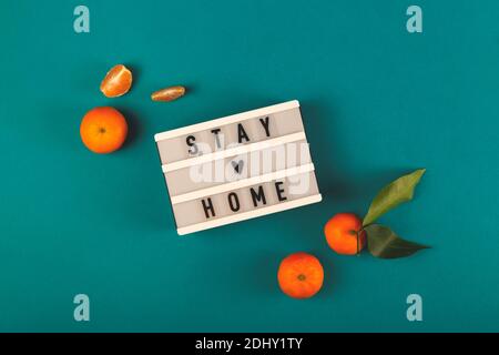 Stay Home written on lightbox among tangerines Stock Photo