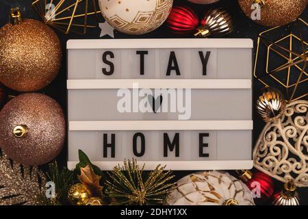 Stay Home written on lightbox among Christmas decorations Stock Photo
