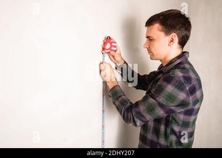 Man worker measuring and marking distance on white wall with measure tape tool and pencil Stock Photo