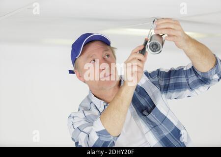 mature man installing closed circuit tv camera Stock Photo