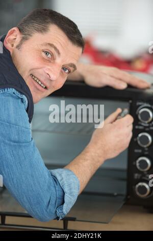 mature man repairing microwave oven in kitchen Stock Photo