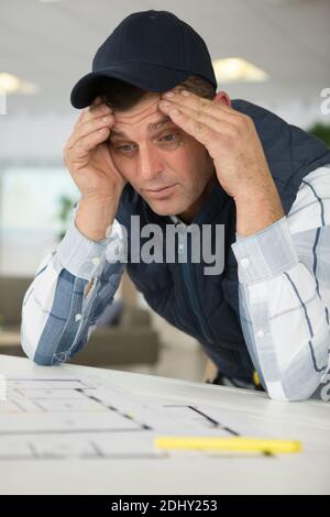 puzzled worker stressing over architectural plans Stock Photo