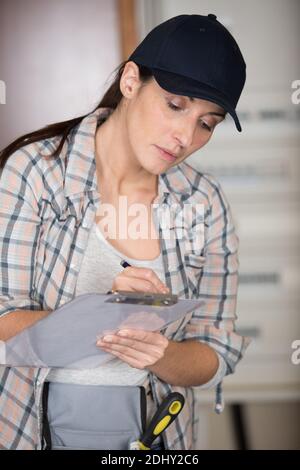 female manual worker writing on a clipboard Stock Photo