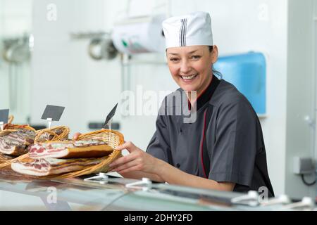 happy woman selling delicious prosciutto meat on market Stock Photo