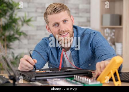 man testing laptop with a multimeter Stock Photo