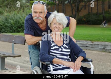 senior man and woman in wheelchair in park Stock Photo