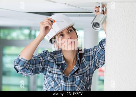 female contractor installing cctv camera inside building Stock Photo