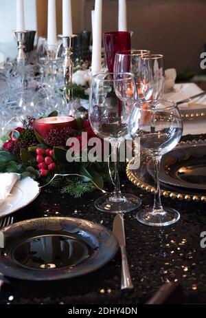 Christmas composition of fir branches, berries and candles on the table. Festive table setting for Christmas dinner on a shiny black tablecloth and ex Stock Photo