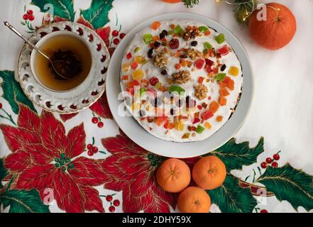 Christmas stollen, panettone, brioche, cake decorated with white icing, marzipan, raisins, dried fruit, a cup of tea and orange tangerines on the fest Stock Photo
