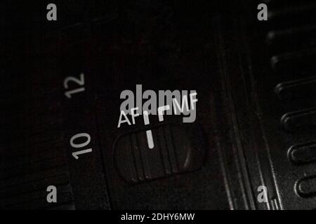 Closeup of the AF MF switch on the camera lens. Slider for changing the autofocus mode. Dark background. Stock Photo