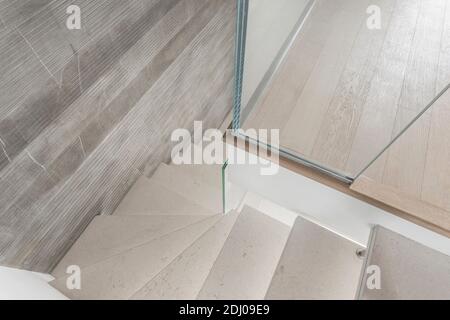 Grey microcement stairs with glass handrail. Stairs viewed from above. Modern design and innovative material. Glass railing. Stock Photo