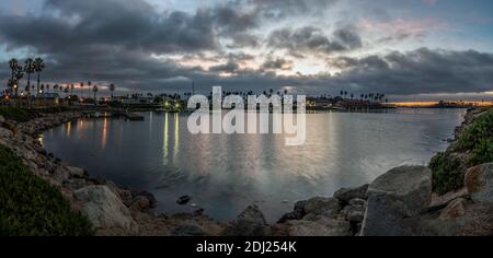 Overcast clouds over marina ocean water with light reflection in ocean surface reveal crescent waning moon and Venus in the predawn sky. Stock Photo