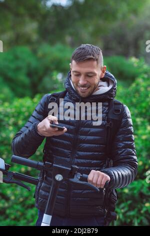 Young man student renting an electric scooter with a smartphone app Stock Photo