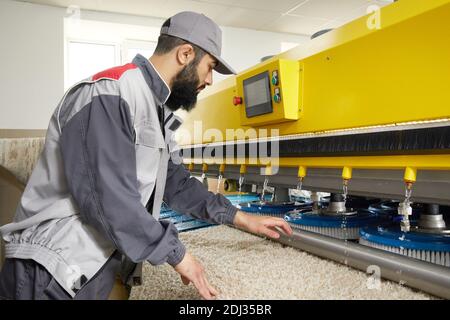 Man operating carpet automatic washing machine in professional laundry service Stock Photo