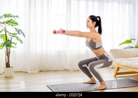 young woman in sportswear doing fitness stretching exercises at home Stock Photo