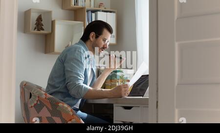 Confident man wearing glasses recording voice message, holding phone Stock Photo