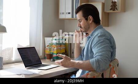 Confident businessman talking on phone, negotiating with partner, using laptop Stock Photo