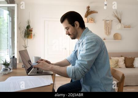 Side view confident serious man wearing glasses working on laptop Stock Photo