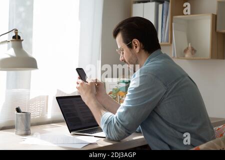 Serious businessman wearing glasses using smartphone, searching information Stock Photo