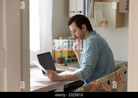 Confident man wearing glasses holding document, reading, working at home Stock Photo