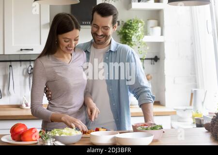 Happy young couple cooking healthy food together in kitchen Stock Photo