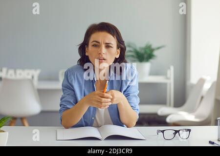 Serious psychologist sitting at desk and looking at web camera listening to client during online consultation Stock Photo