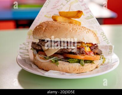 Juicy double cheeseburguer with bacon, tomato, salad and sauces. Close Up Stock Photo