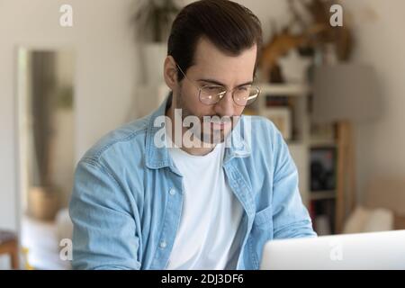 Close up serious focused man wearing glasses using laptop, working Stock Photo