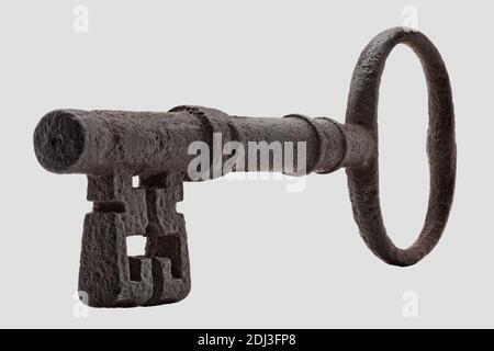 Antique iron key seen in oblique perspective against a plain light background Stock Photo