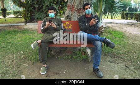 Friends sitting on bench Wearing Face Mask Stock Photo