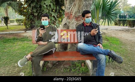 Friends sitting on bench Wearing Face Mask Stock Photo