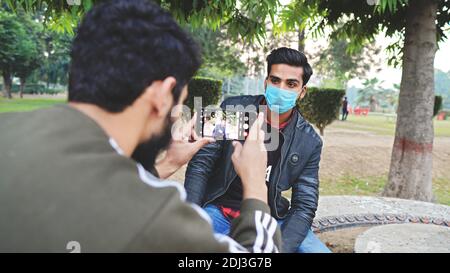 person taking photo of his friend wearing face mask Stock Photo